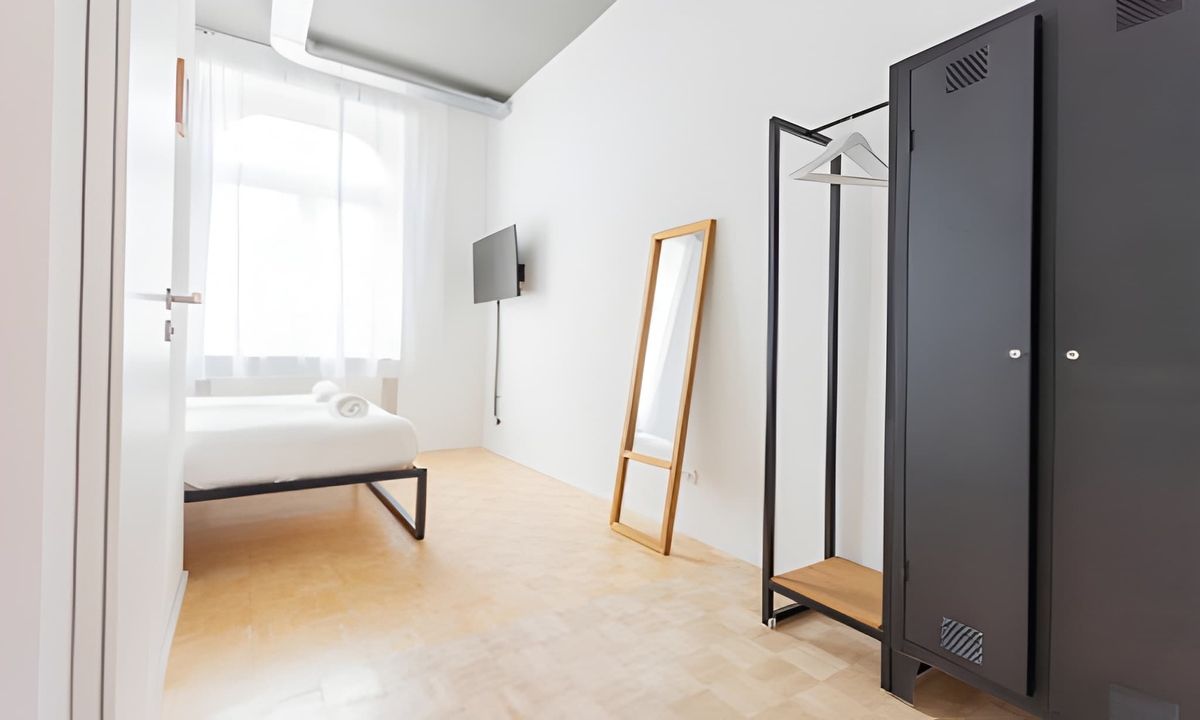 Functional furnishings including a wardrobe and coat rack in the bedroom.