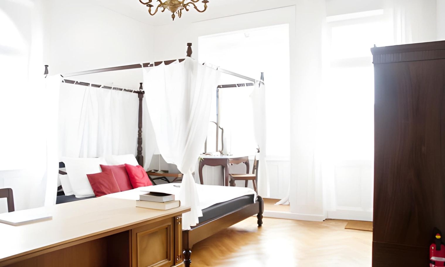 Helles Schlafzimmer mit einem eleganten Vorhangbett und einem Schreibtisch.